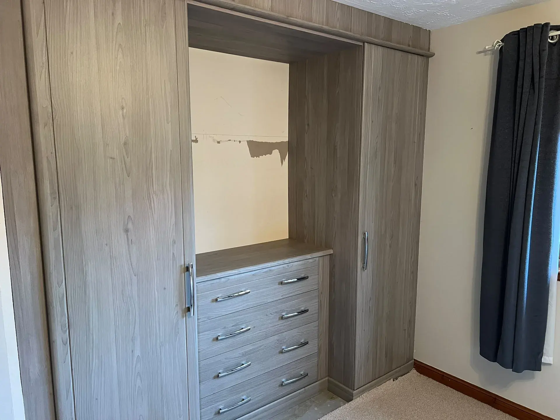 Fitted wardrobe with drawers between tall cupboards