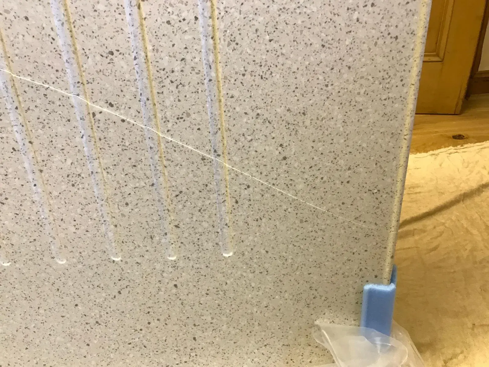 Crack across a speckled worktop beside draining grooves