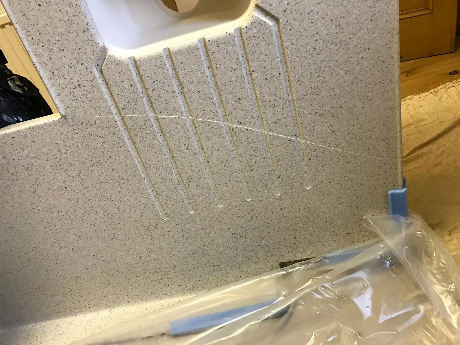 Speckled sink worktop with a crack across the drainer