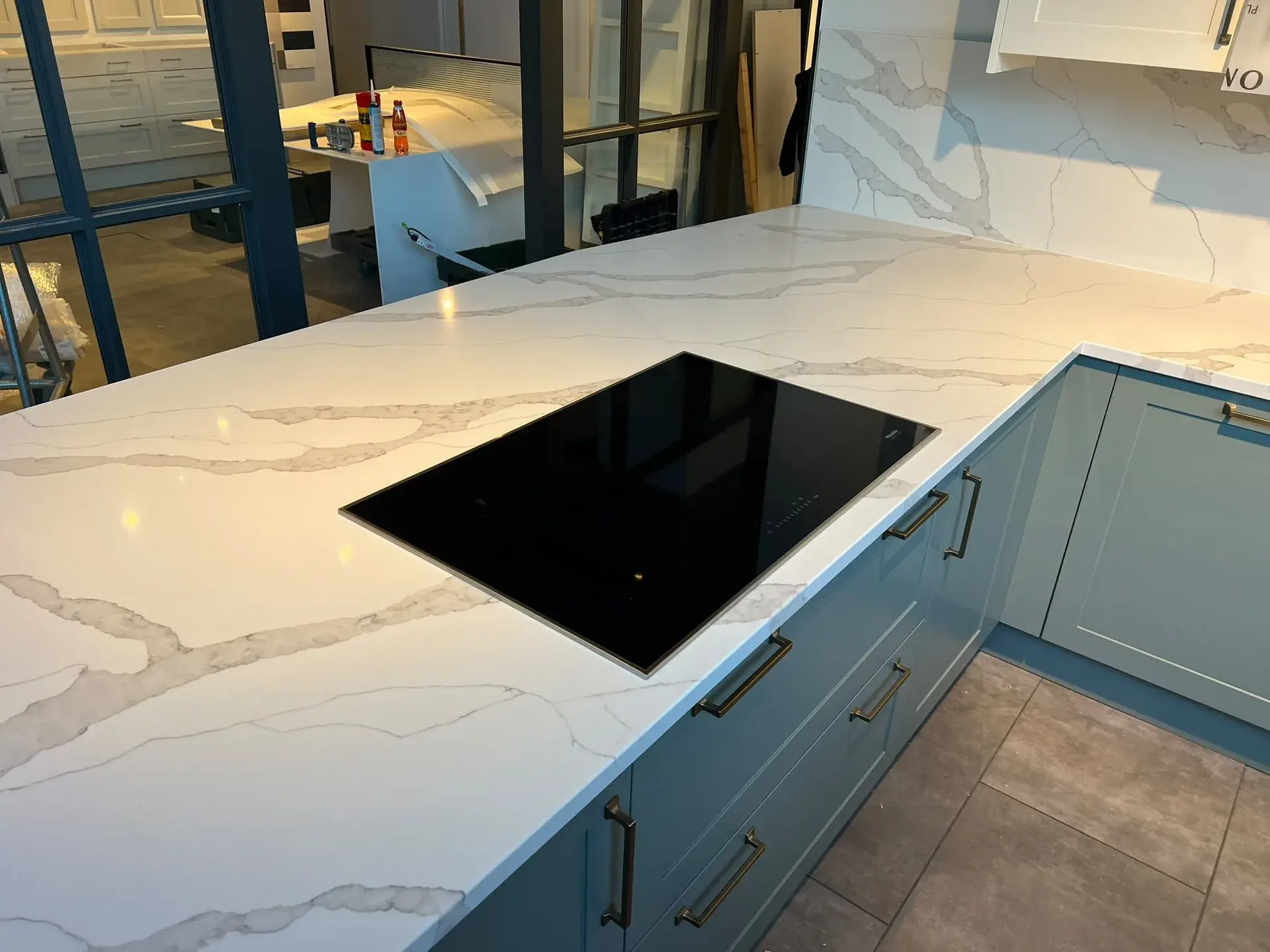 Pale veined worktop surrounding a black hob