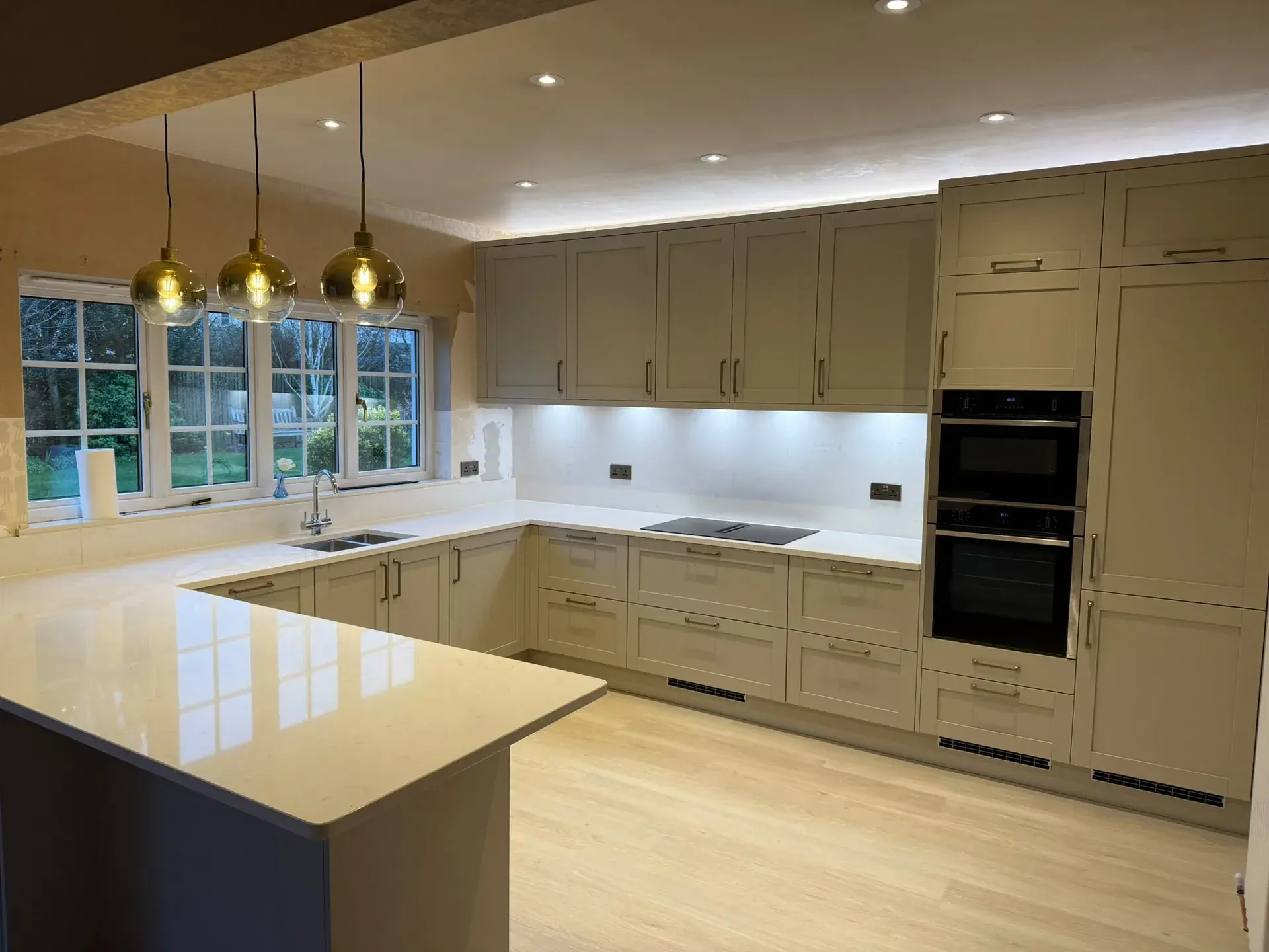Open-plan cream kitchen with an island, pendant lights and timber flooring